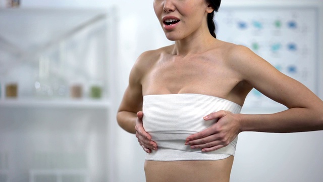 女人在弹性贴合乳房压迫触摸包裹，手术后感到疼痛视频下载