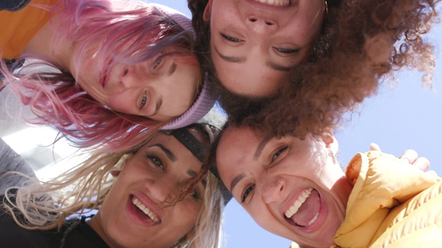 4个微笑的年轻女人在一群-头在一起从下面拍摄视频素材
