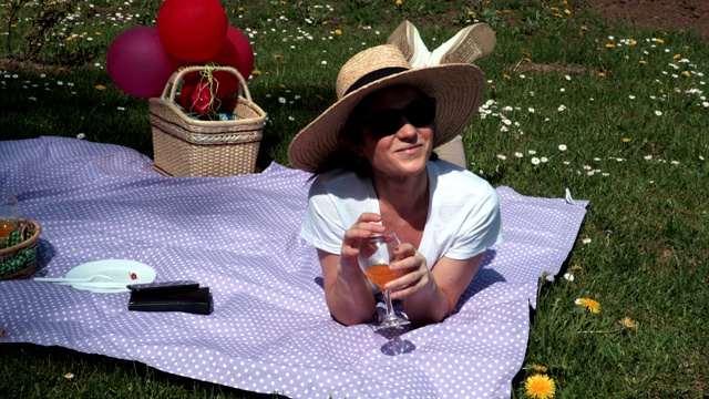 一个女人躺在野餐毯子上喝酒视频下载