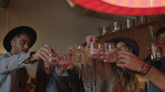 一群朋友举办了一个狂野的家庭聚会，举起他们的酒杯，向他们在沙发上看手机的朋友干杯。视频下载