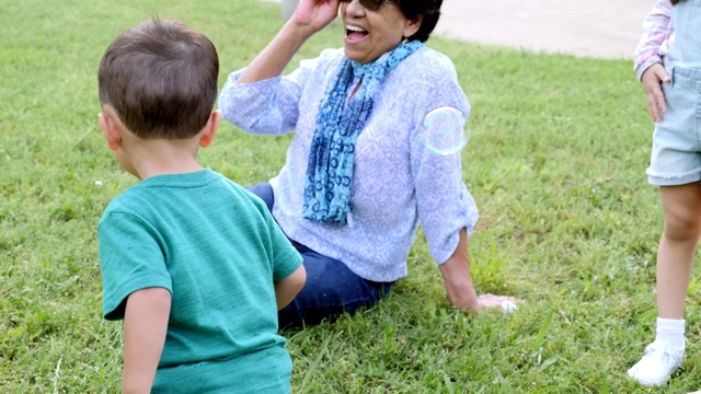 蹒跚学步的小男孩和他奶奶玩泡泡视频素材