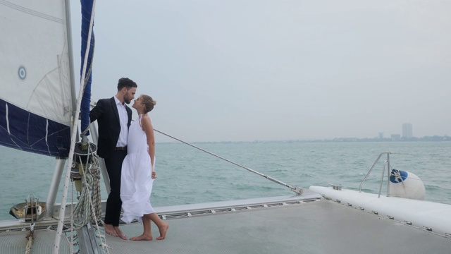 情侣们在浪漫的帆船上，快乐的情侣们在帆船上庆祝，享受美丽的爱情概念视频素材