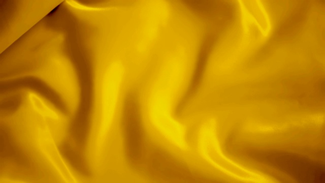 黄金色波浪光滑的丝绸面料在风中荡漾纹理背景视频素材