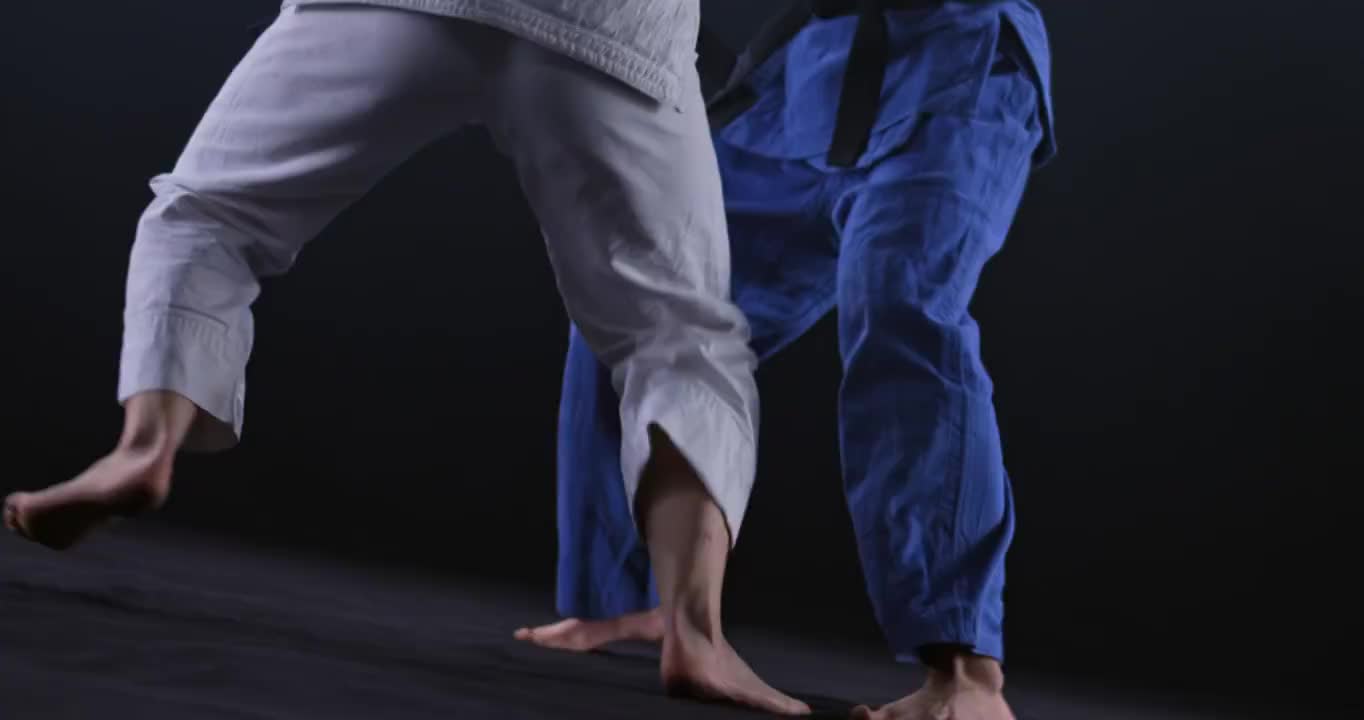 SLO MO女柔道运动员在白色的服装扔她的对手在蓝色的地板上视频素材