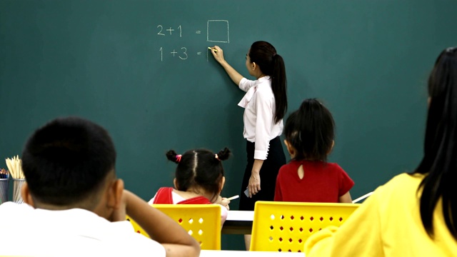 亚洲老师在绿板上写数学题。视频下载