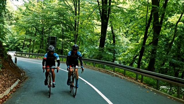 两个骑自行车的男性在山路上坡视频下载