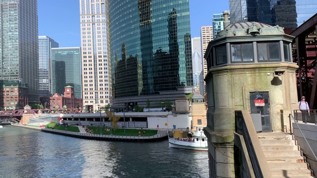 图尔船穿过湖街大桥下面，在那里通勤者和高架列车运行在芝加哥河的轨道上。视频素材