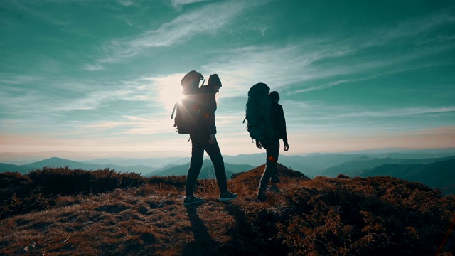 在夕阳的背景下，徒步旅行者向那座山走去。慢动作视频素材