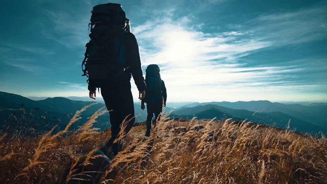 在阳光明媚的背景下，男人和女人走在山上。慢动作视频素材