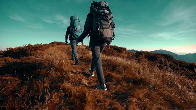 背着露营背包的徒步旅行者向山顶走去。慢动作视频素材