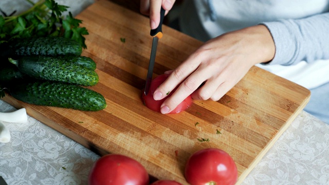 靠近女人的手用刀在木板上切西红柿。概念的蔬菜视频下载