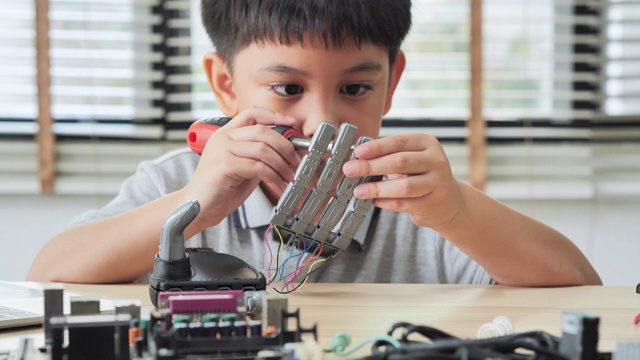 男孩在家里用电脑制作和编程，并制作一个机器人手臂作为学校的科学项目。他对自己的工作非常满意。教育、儿童、技术、科学是人们的理念视频下载