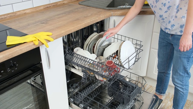 女人的手放在白色的脏盘子和关闭洗碗机与肮脏的白色盘子。手特写，侧视图。视频下载
