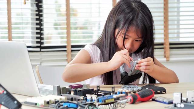女孩在家里用电脑构建和编程，并建造一个机器人手臂作为学校的科学项目。她对自己的工作非常满意视频素材