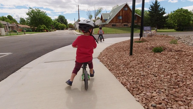 两名白人男孩(四岁和五岁)在一个停车标志前停下，在阴天下骑着自行车准备穿过居民区街道时，向两边看汽车视频素材