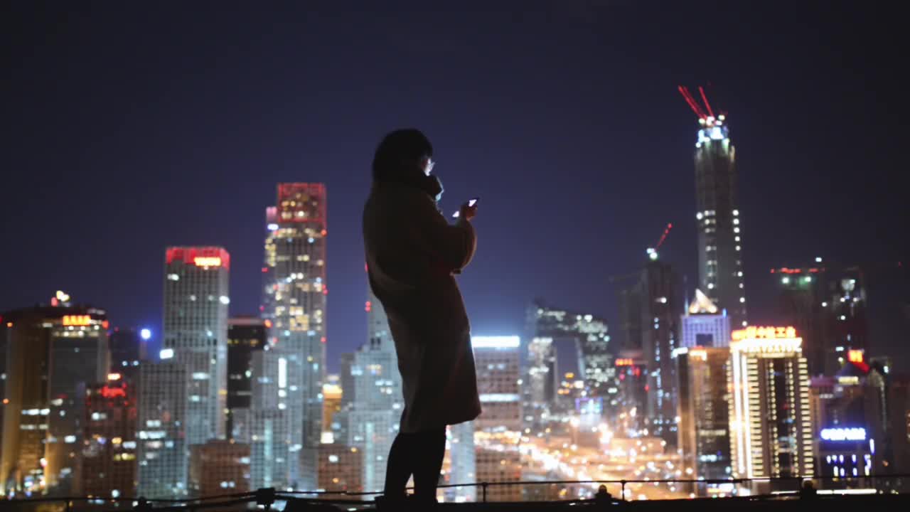 女性晚上在城市使用智能手机视频下载