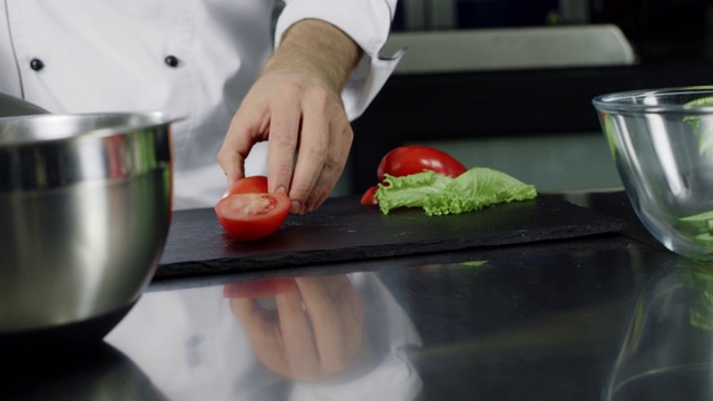 厨师在厨房制作新鲜的沙拉。特写厨师用手切番茄。视频素材