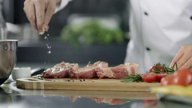 男厨师在厨房里腌制肉。特写厨师在工作场所用手腌制牛排视频素材