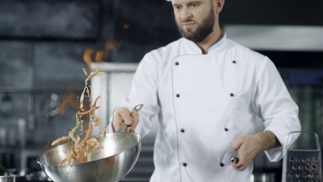 厨师用燃烧的火慢动作烹饪食物。专注的厨师扔食物视频素材