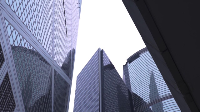 玻璃幕墙商业大厦在香港城市的底部视图。办公大楼和摩天大楼外立面的玻璃窗户在现代化的市中心。发达城市的建筑视频素材