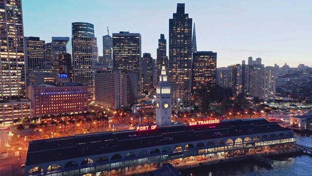 无人机在旧金山城市的天际线和轮渡大楼的夜间吊车下揭示拍摄视频素材