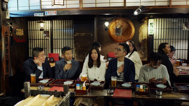 手持拍摄的人坐在酒吧和桌子上拥挤的东京餐厅视频素材