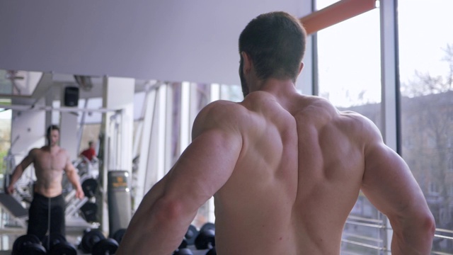 在健身房进行力量训练前，专业的健身师会在镜子前做热身运动视频下载