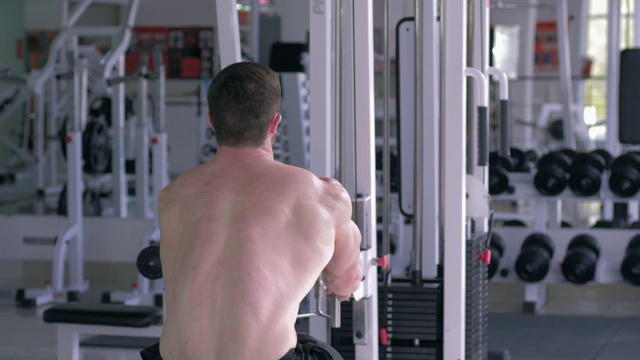 力量训练，强壮的裸体健美男子做肌肉建设锻炼在牵引模拟器，而工作在体育俱乐部的身体视频下载