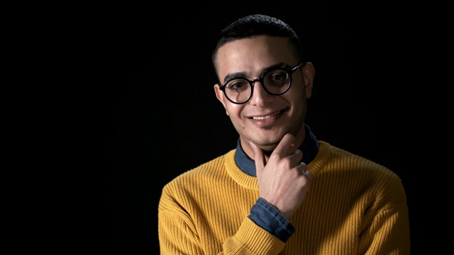 年轻微笑的阿拉伯男子在黑色背景视频下载