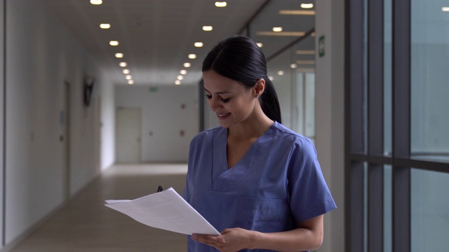 美丽的护士阅读文件，然后对着镜头微笑视频素材