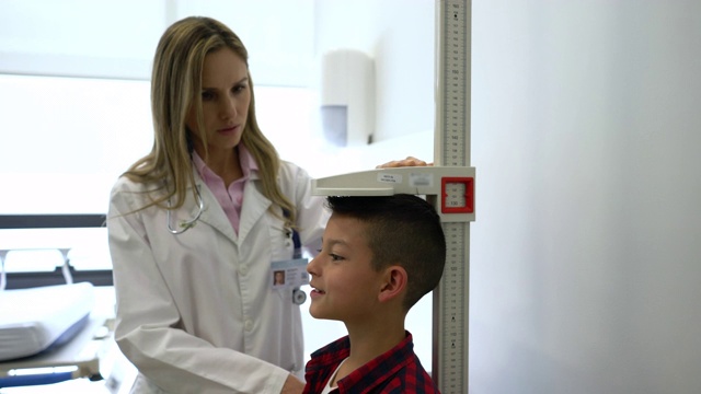 友好的儿科医生在会诊时测量兴奋的小男孩的身高视频素材