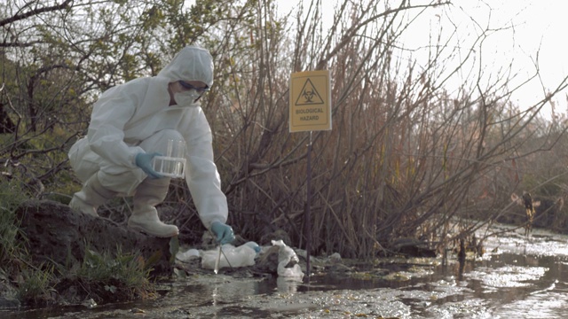 在自然中生物的危险性，危险物质研究人员进入防护服取受感染的水样在试管中测试在污染的湖与指针符号bi视频素材
