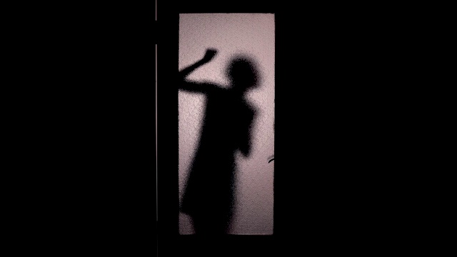 惊恐的女人侧影敲着玻璃门，检查门把手，恐惧，逃跑视频素材