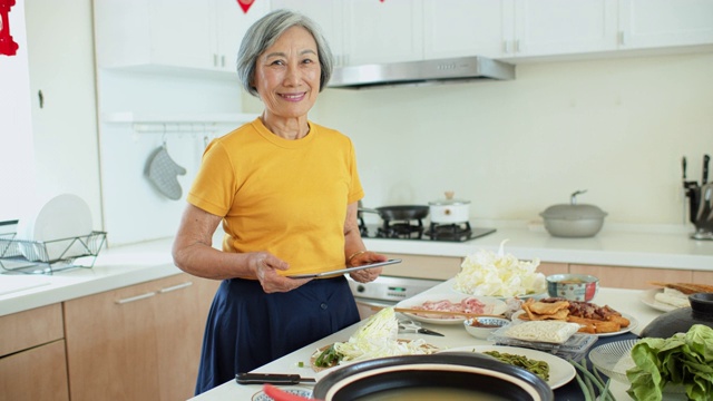 高级亚洲妇女在家烹饪平板电脑的肖像视频素材