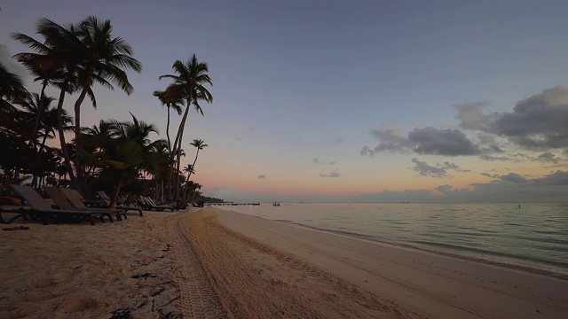 多米尼加共和国蓬塔卡纳热带岛屿海滩上的日出。拖拉机清砂视频素材