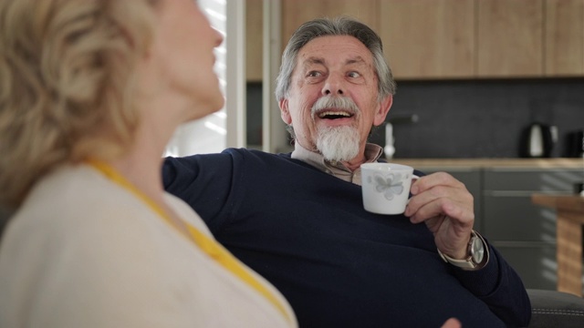 老夫妇在客厅的沙发上喝咖啡聊天视频素材
