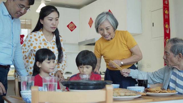 中国新年的家人坐下来给餐桌上带来食物视频素材