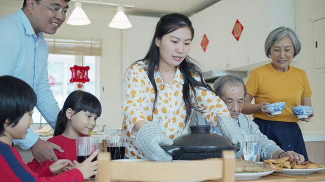 妈妈在春节给父母和孩子端火锅视频素材
