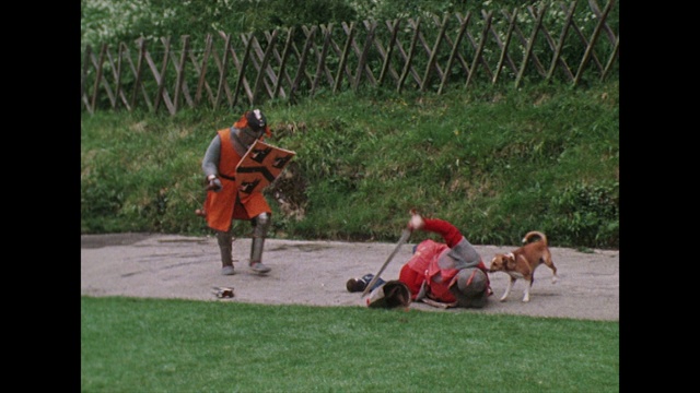 两个骑士用剑战斗，一条狗对着他们吠叫;1975视频素材
