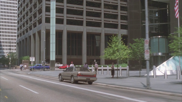 在市中心的城市街道上，广角车正向前行驶。路易斯安那摩天大楼和高层写字楼或公寓。人行道上的人或行人。视频下载