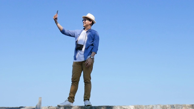 快乐的亚洲游客使用智能手机与朋友和家人在海滩上视频通话，生活方式的概念。视频下载