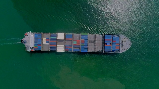 鸟瞰图集装箱船到海港，在起重机桥上装卸集装箱，进行物流，航运，进出口或运输。视频素材