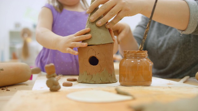 老师在帮一个小女孩给陶瓷鸟屋盖屋顶视频下载