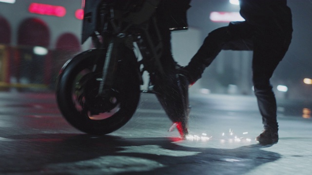 一名特技车手在一个下雨的停车场里，在自行车后座上滑行，火花四溅。视频下载