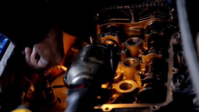 机修工戴着手套的手的特写，他正在修理汽车的引擎。视频素材