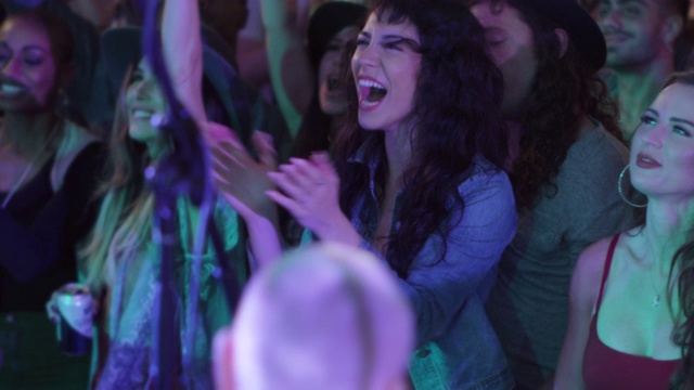 在一场流行音乐节的前排，一位千禧一代的波西米亚女子一边摇滚一边尖叫视频素材