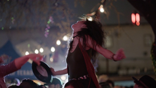 在一个流行音乐节上，一名千禧一代的波西米亚女子骑在她的另一半的肩膀上摇滚起来视频素材