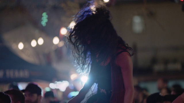 SLO MO:在一个流行音乐节上，一名千禧一代的波西米亚女子骑在她的另一半的肩膀上，双手向空中挥舞视频素材