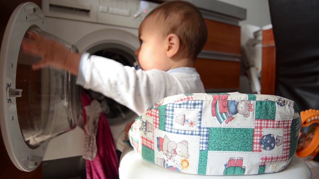 可爱的六个月大的小男孩帮助洗衣服-把洗好的衣服从洗衣机里拉出来视频素材