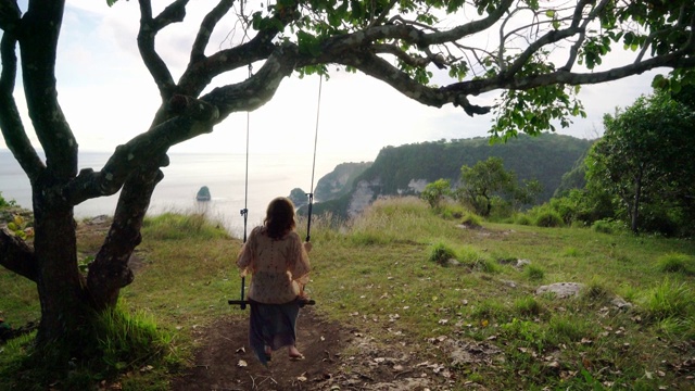 在努沙佩尼达附近的海边荡秋千的女人的风景视频素材